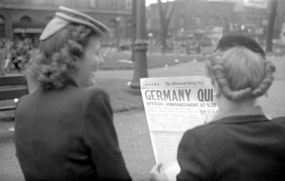 Femmes lisant un journal annoncant la capitulation de l'Allemagne nazie